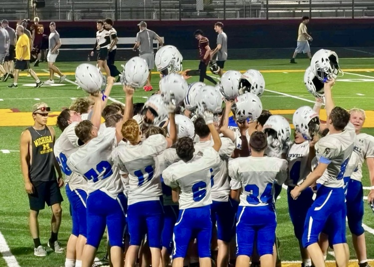 picture of freshman football team with their helmets up in a huddle
