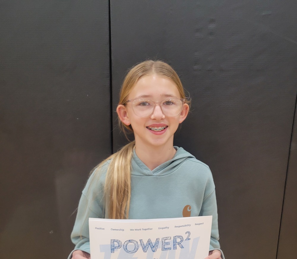 female student with long blonde brown hair and glasses receiving her student of the month selection