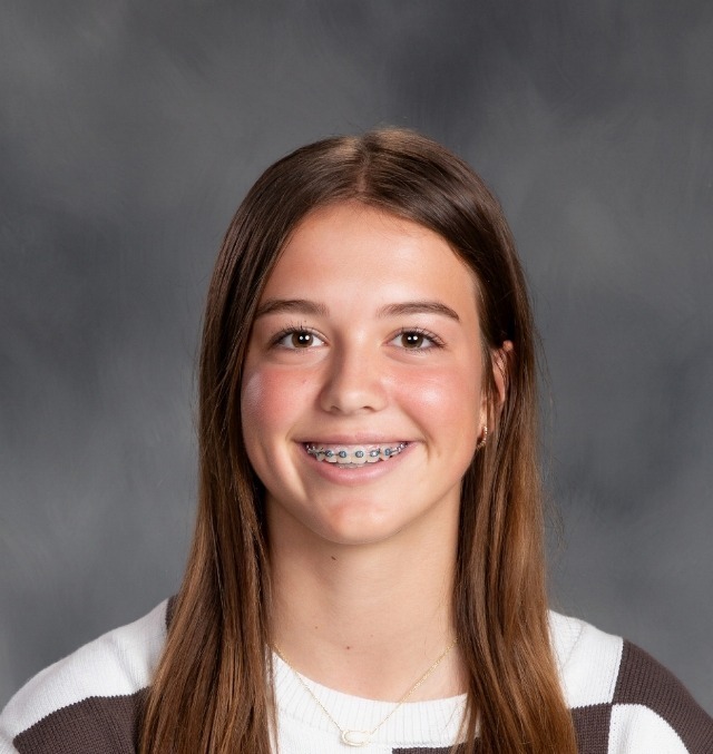 female student with long brown hair and a brown and white checked tshirt