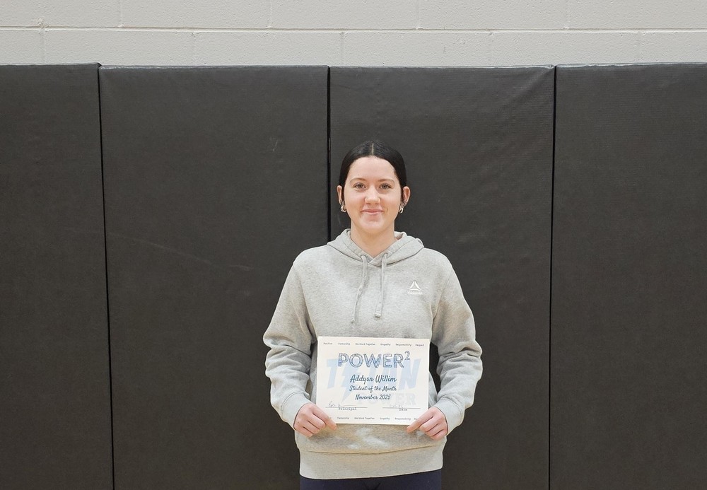 female student with brown hair, gray hoodie and blue jeans