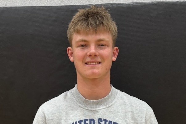 male student with light brown curly hair and a grey sweatshirt
