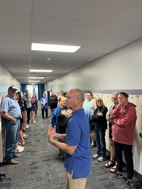 several staff members listening to the presenter in the hallway during an activity