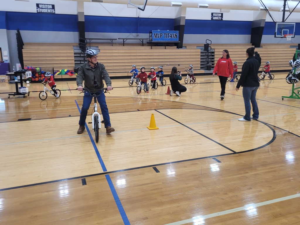 adult male riding a strider bike with a black and white helmet