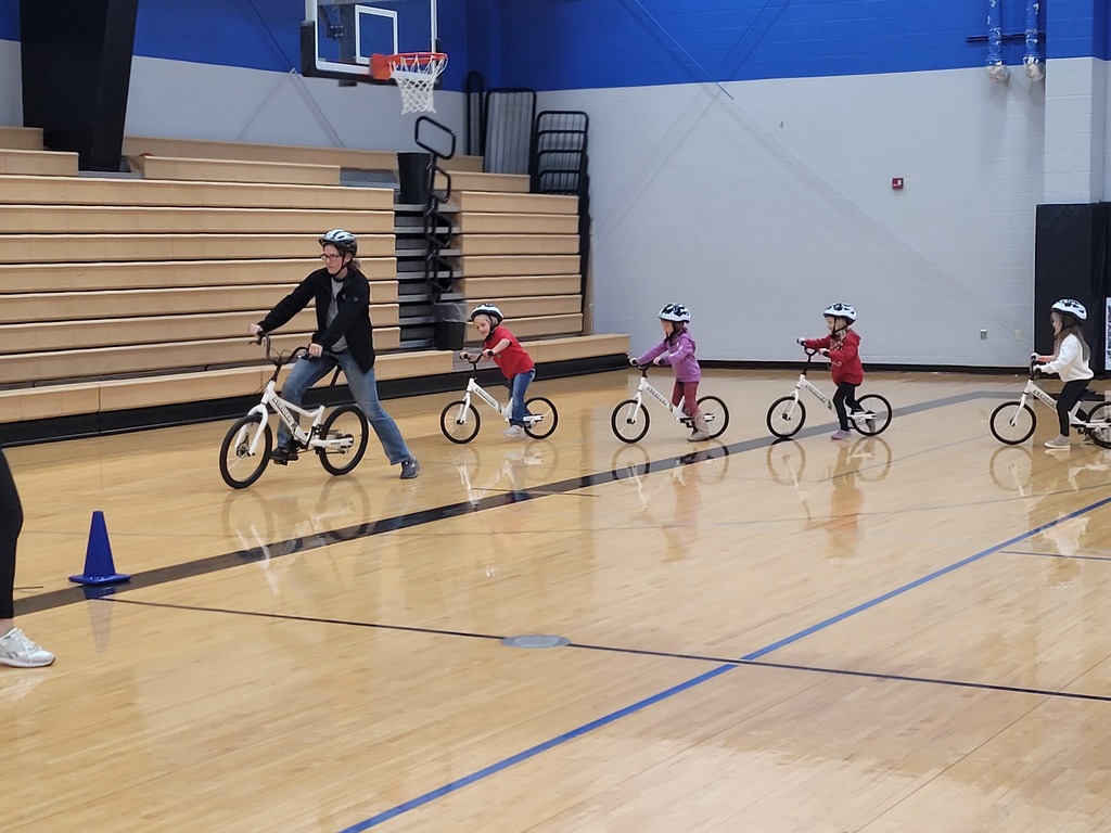 female adult leading the classes around the gym on their new Strider bikes