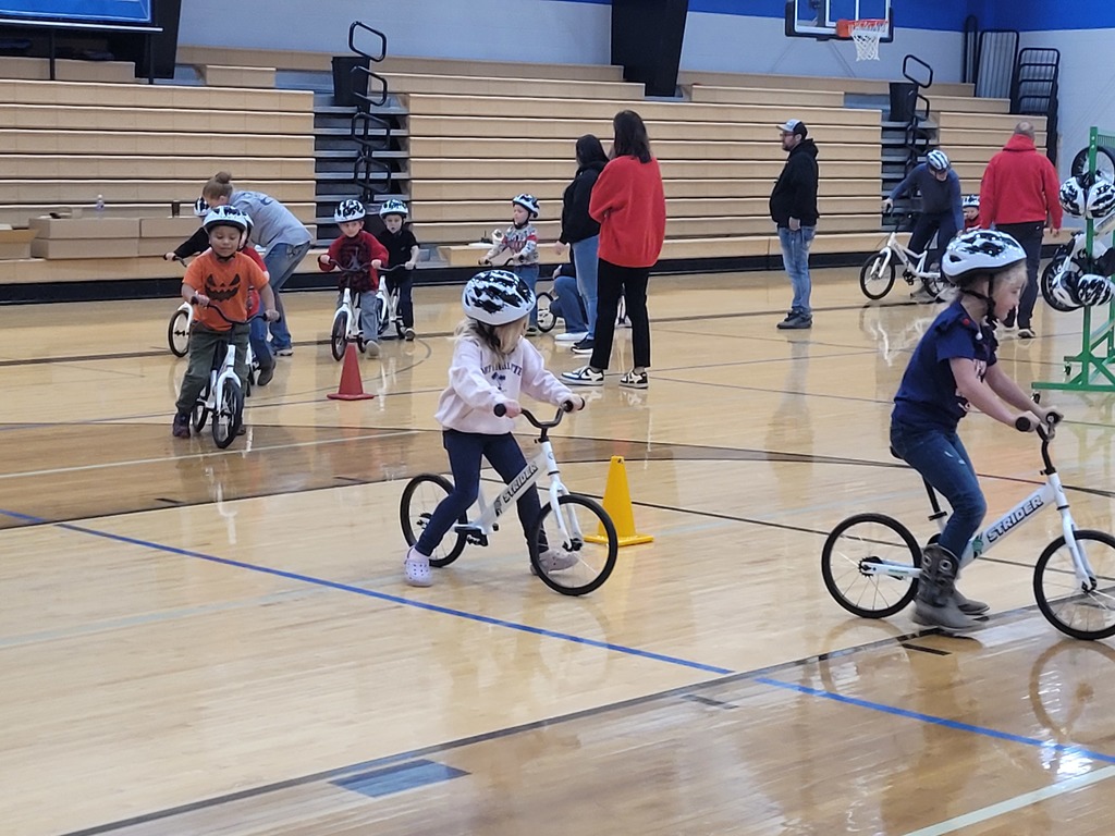 kids riding their new strider bikes around the gym