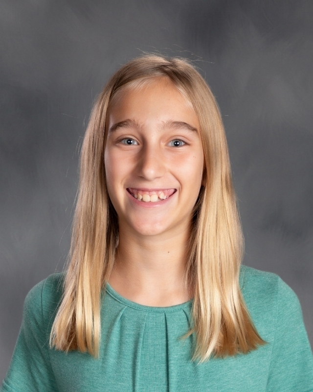 female student with long blonde brown hair with a green top