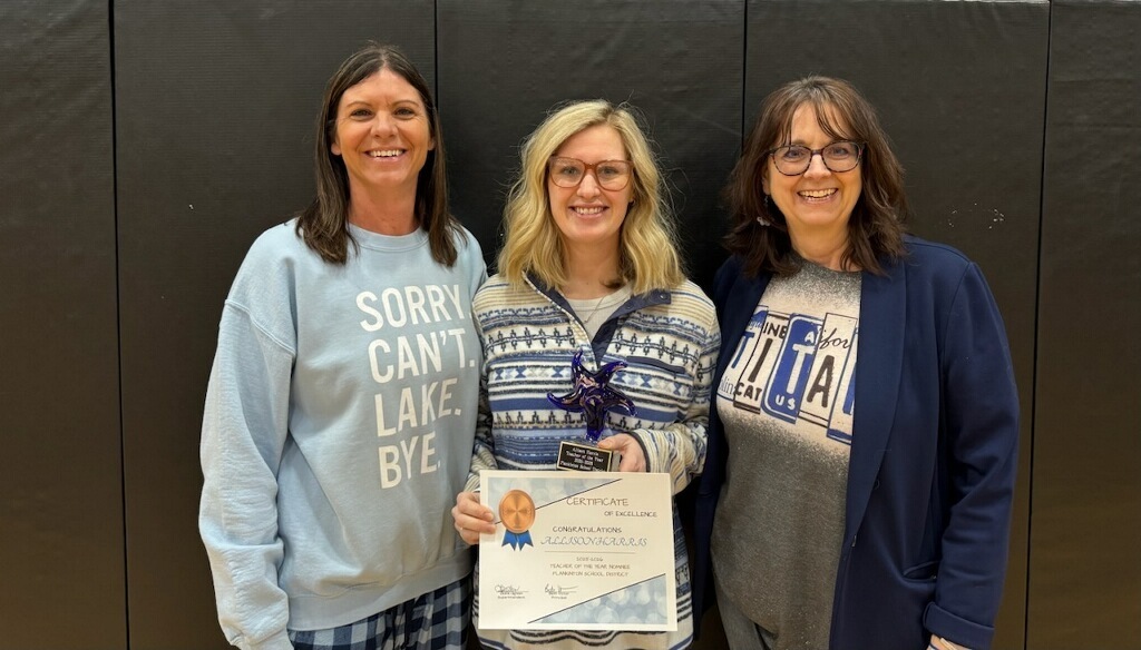the teacher of the year selectee being honored and surrounded by the principal and the superintendent