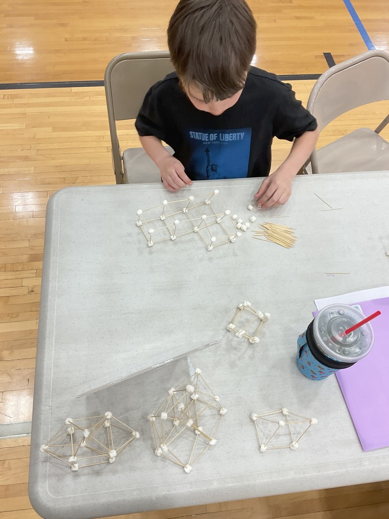 elementary age male student creating a marshmallow shape with marshmallow and spaghetti
