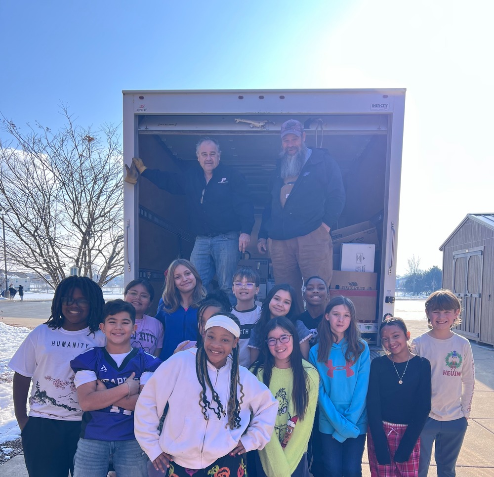 students posing for picture in front of truck