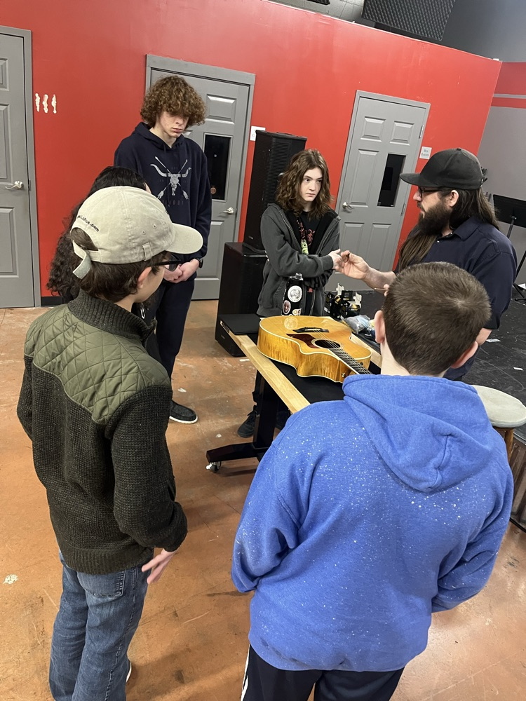 guitar students learning how to string an acoustic guitar