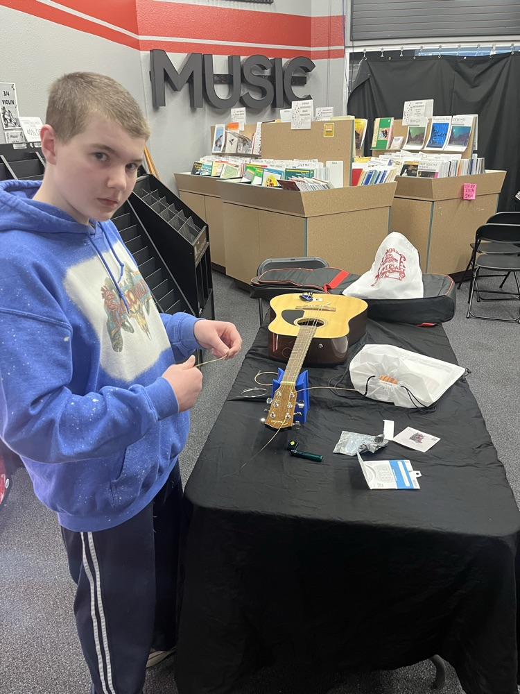 Guitar students practicing stringing an acoustic guitar