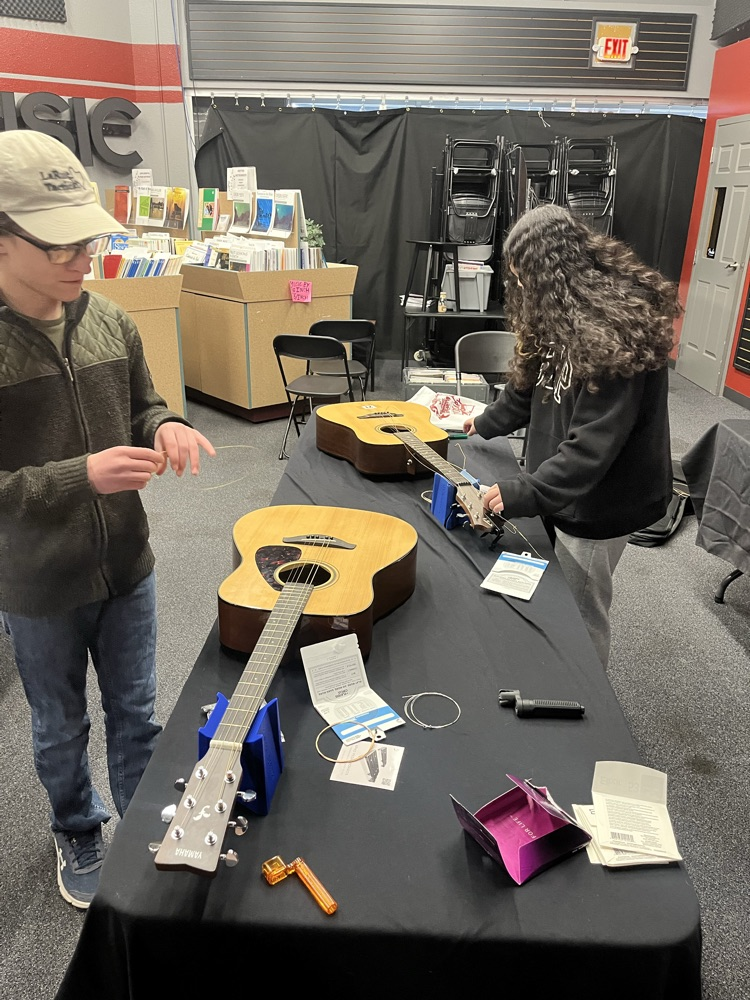 Guitar students practicing stringing an acoustic guitar