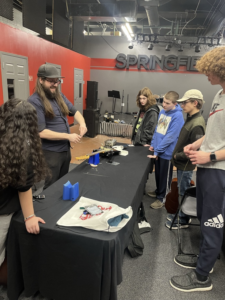 guitar students learning how to string an electric guitar