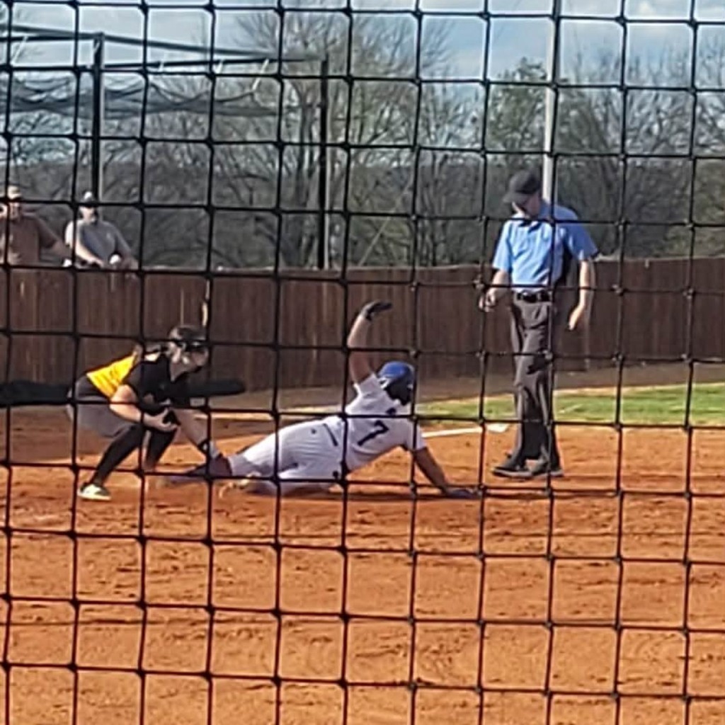 softball player tagging a runner put at 3rd base