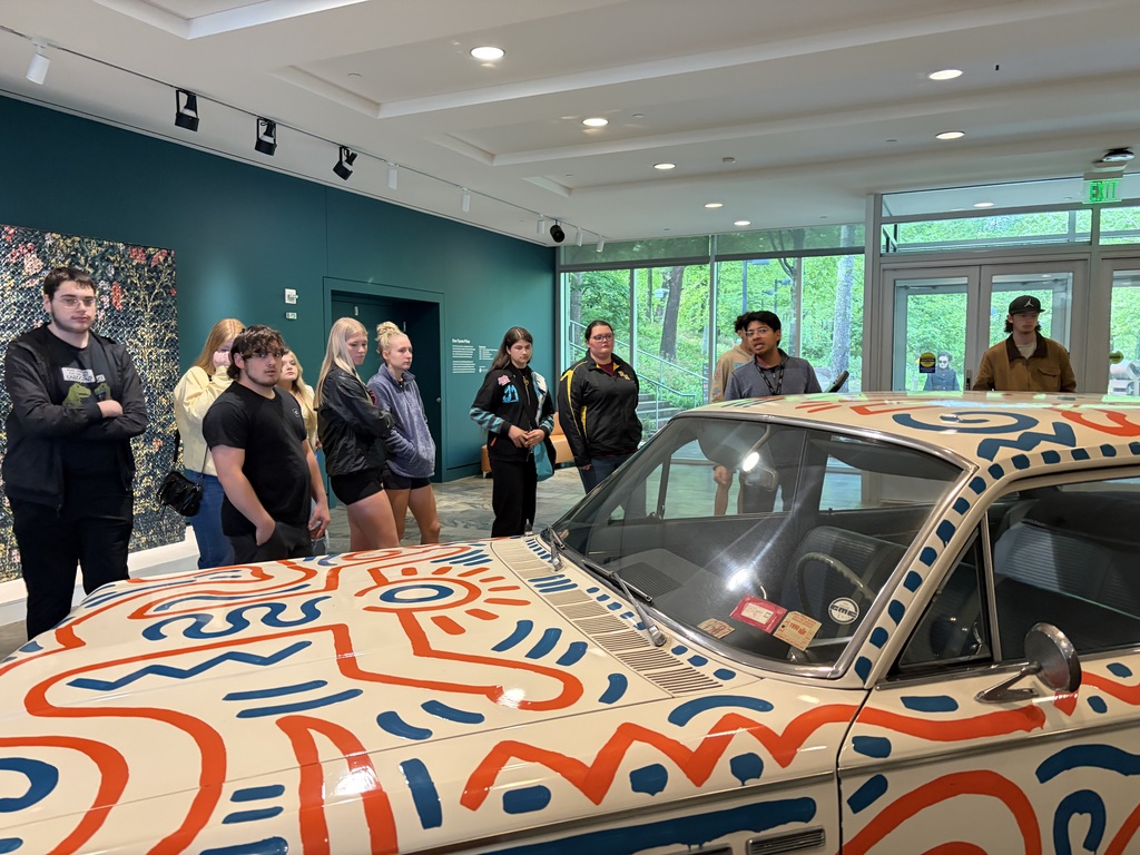 Students look at a car. 