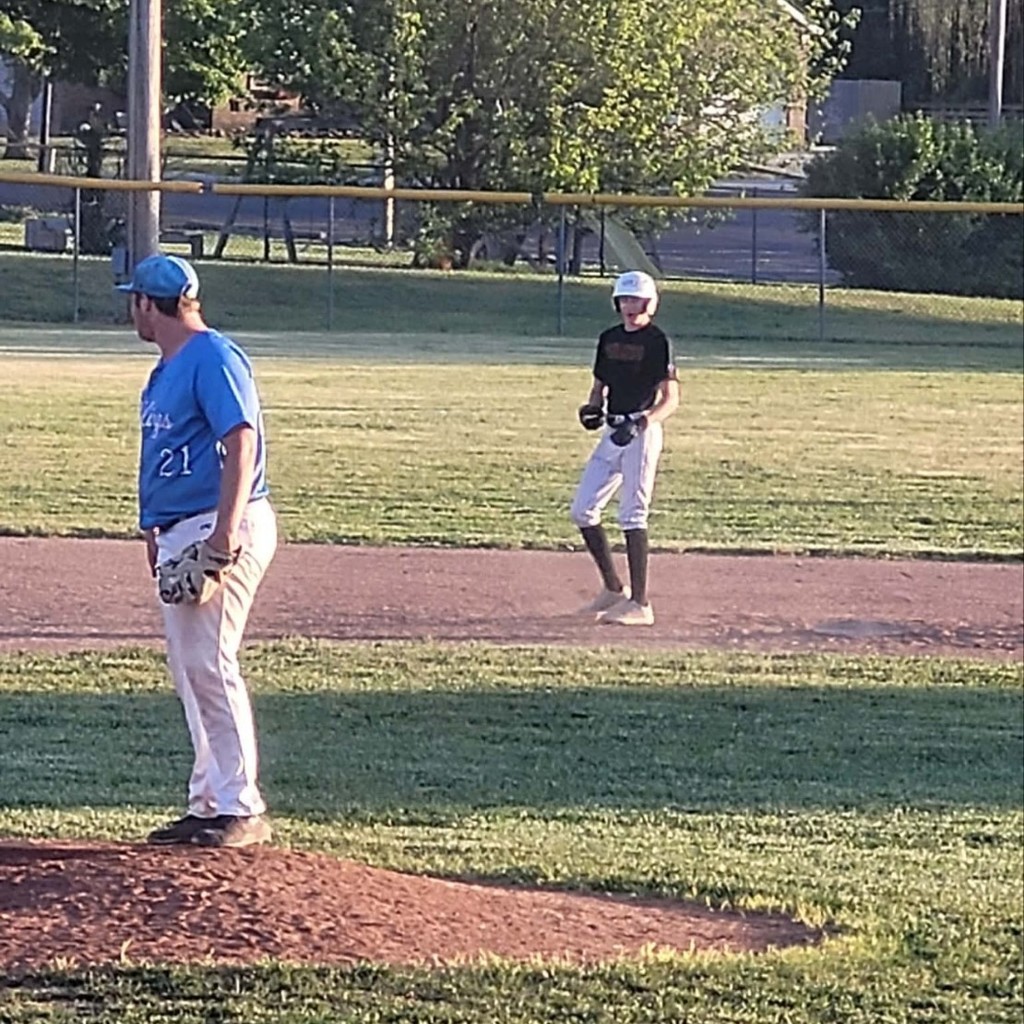 hs baseball pitcher and a player leading off of 2nd base
