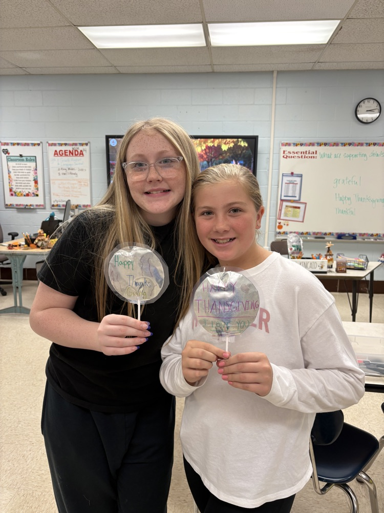Students in Mrs. Kincaid’s class stand in a classroom holding homemade Mylar-style balloons shaped and decorated for Thanksgiving. 