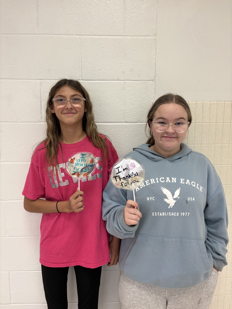 Students in Mrs. Kincaid’s class stand in a classroom holding homemade Mylar-style balloons shaped and decorated for Thanksgiving. 
