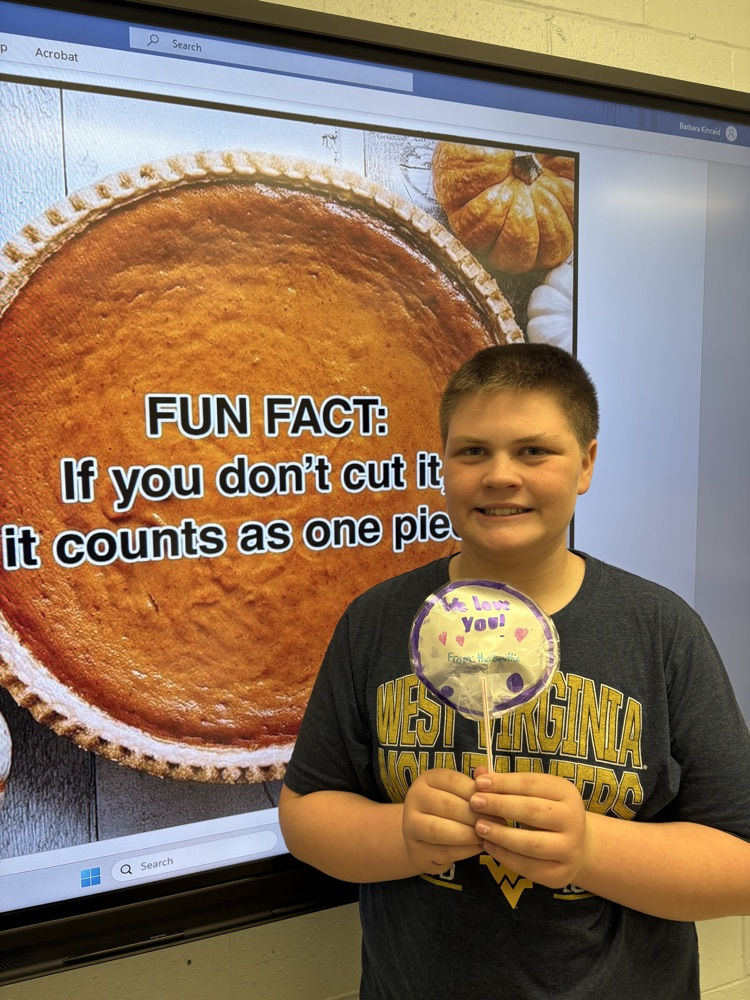 Students in Mrs. Kincaid’s class stand in a classroom holding homemade Mylar-style balloons shaped and decorated for Thanksgiving. 
