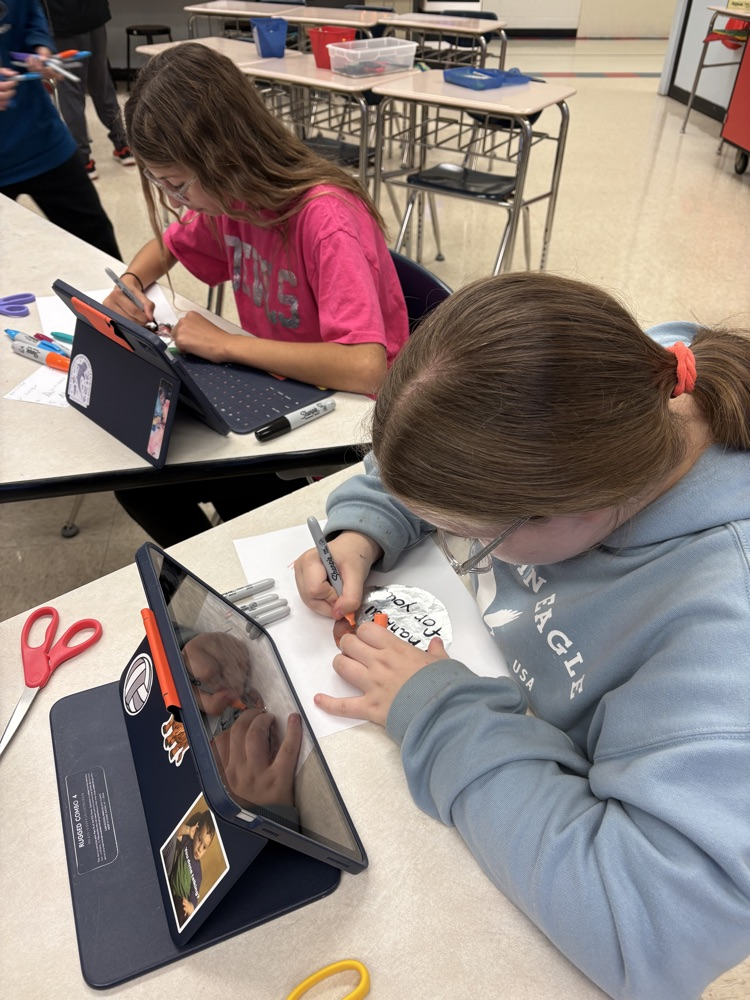 Students in Mrs. Kincaid’s class stand in a classroom holding homemade Mylar-style balloons shaped and decorated for Thanksgiving. 