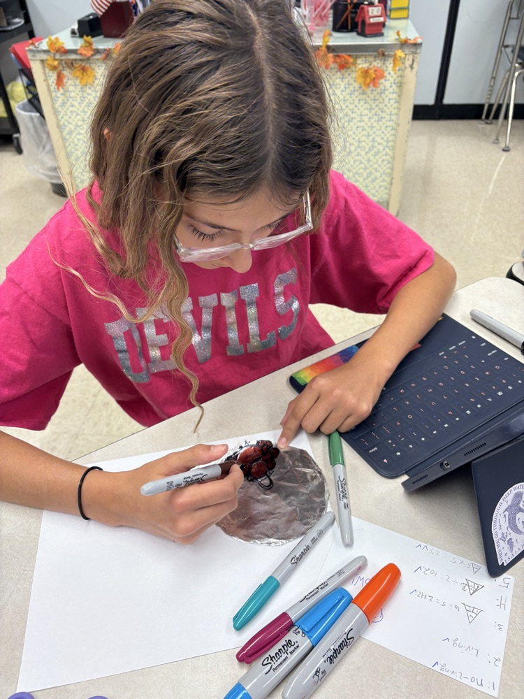 Students in Mrs. Kincaid’s class stand in a classroom holding homemade Mylar-style balloons shaped and decorated for Thanksgiving. 