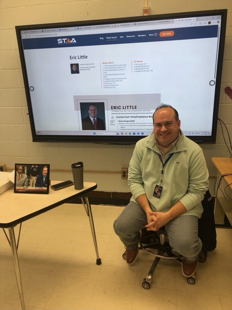 TV and radio play-by-play announcer Eric Little speaks to a middle school journalism class, sharing insights about broadcasting while students listen attentively.
