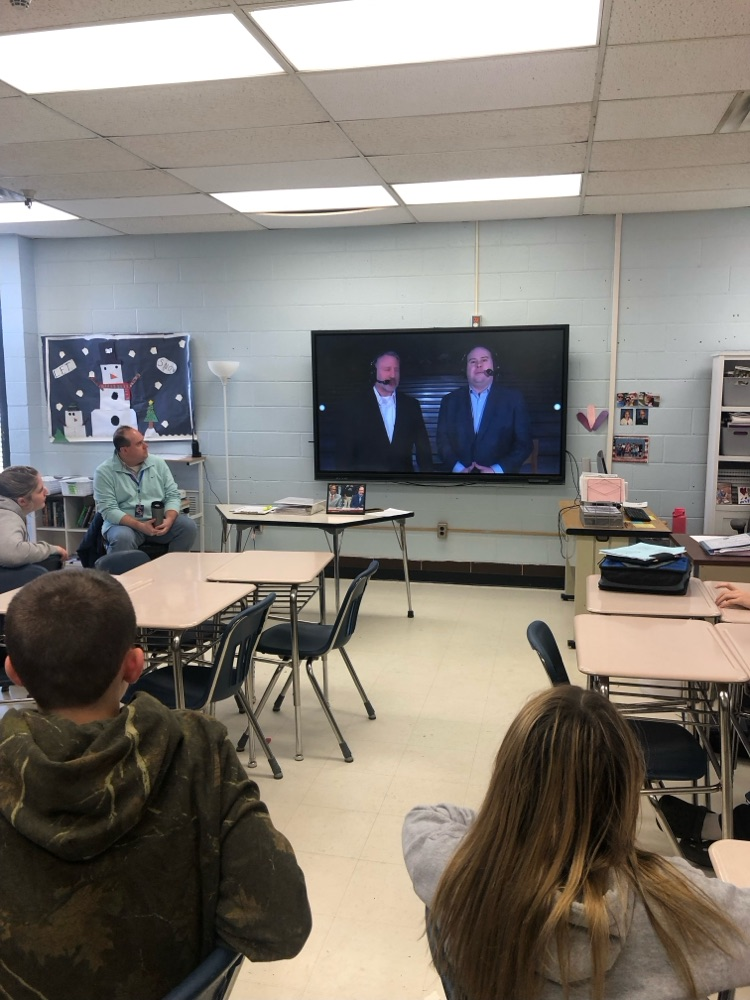 TV and radio play-by-play announcer Eric Little speaks to a middle school journalism class, sharing insights about broadcasting while students listen attentively.