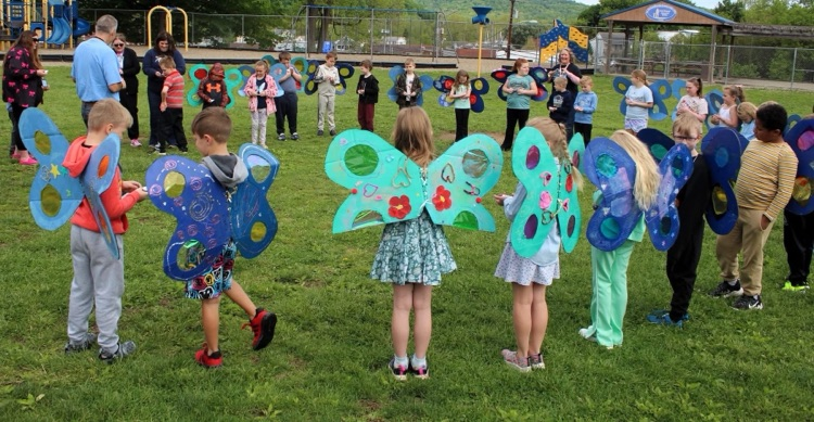 students and butterfly costumes releasing butterflies into the air outside