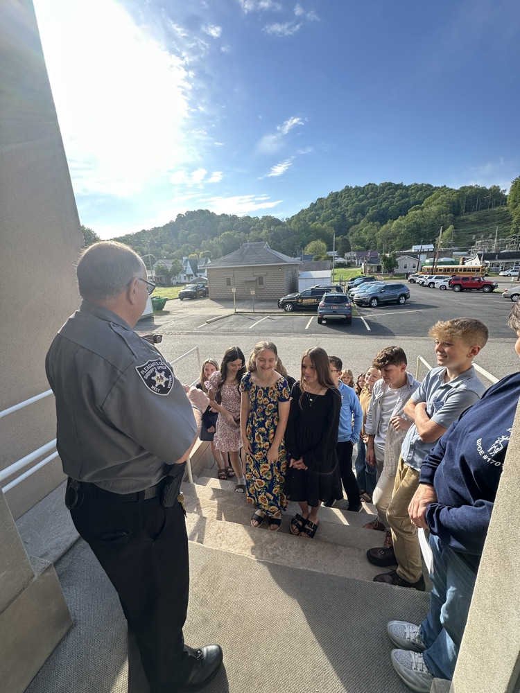 Seventh grade students standing inside the Pleasants County Courthouse, interacting with courthouse employees and observing daily operations during an educational field trip.