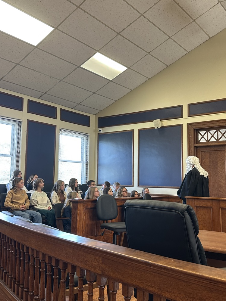 Seventh grade students standing inside the Pleasants County Courthouse, interacting with courthouse employees and observing daily operations during an educational field trip.