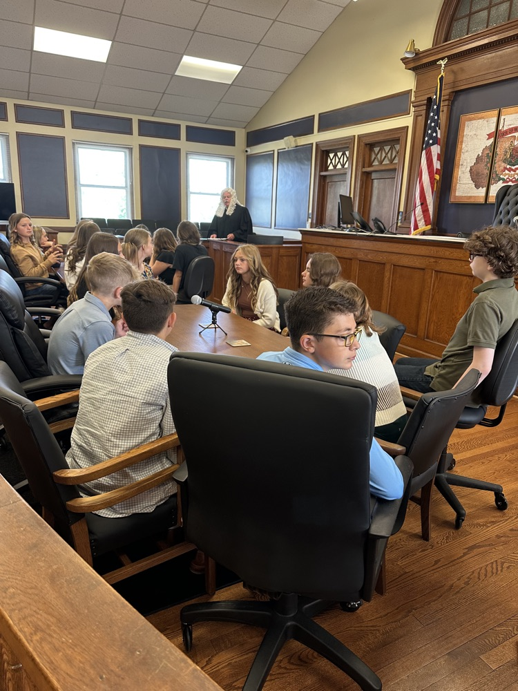 Seventh grade students standing inside the Pleasants County Courthouse, interacting with courthouse employees and observing daily operations during an educational field trip.