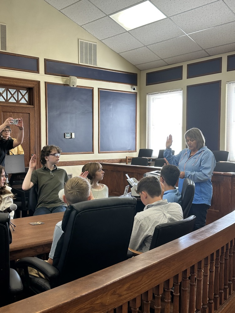 Seventh grade students standing inside the Pleasants County Courthouse, interacting with courthouse employees and observing daily operations during an educational field trip.