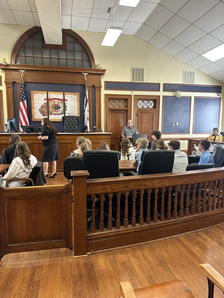 Seventh grade students standing inside the Pleasants County Courthouse, interacting with courthouse employees and observing daily operations during an educational field trip.