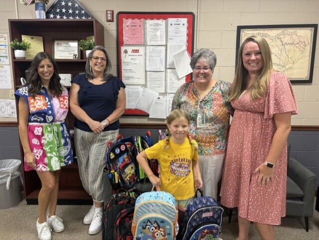 Asst. Principal at PCMS, Catie Hamilton and Principal at Belmont Elementary, Kayla Spitzer pose for a photo with Marietta Memorial representatives as they receive back-to-school supplies as a donation.