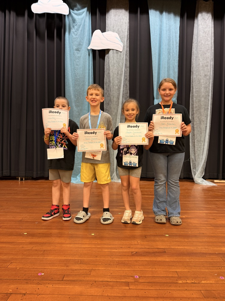 Second grade students proudly pose with their i-Ready Math Champion of the Week certificates, celebrating their hard work and achievement.