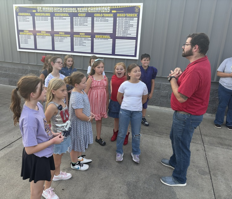 Fourth grade BES choir students performing the Star-Spangled Banner at a Pleasants County Middle School football game, directed by Mr. Negie.