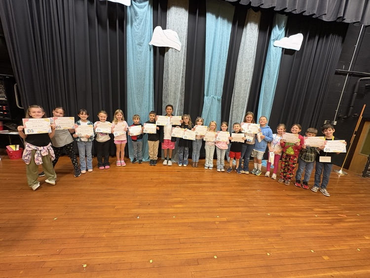 Second grade students proudly display English awards for completing their lessons.