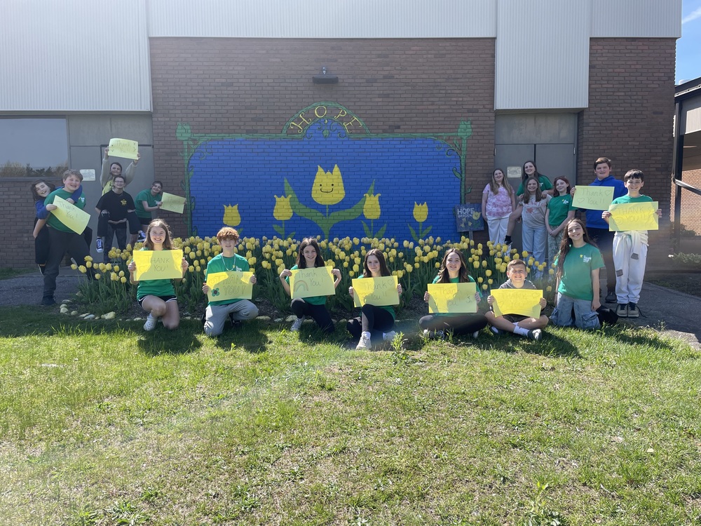 Student ambassadors in the Yellow Tulip Project holding signs that say "Thank you!"