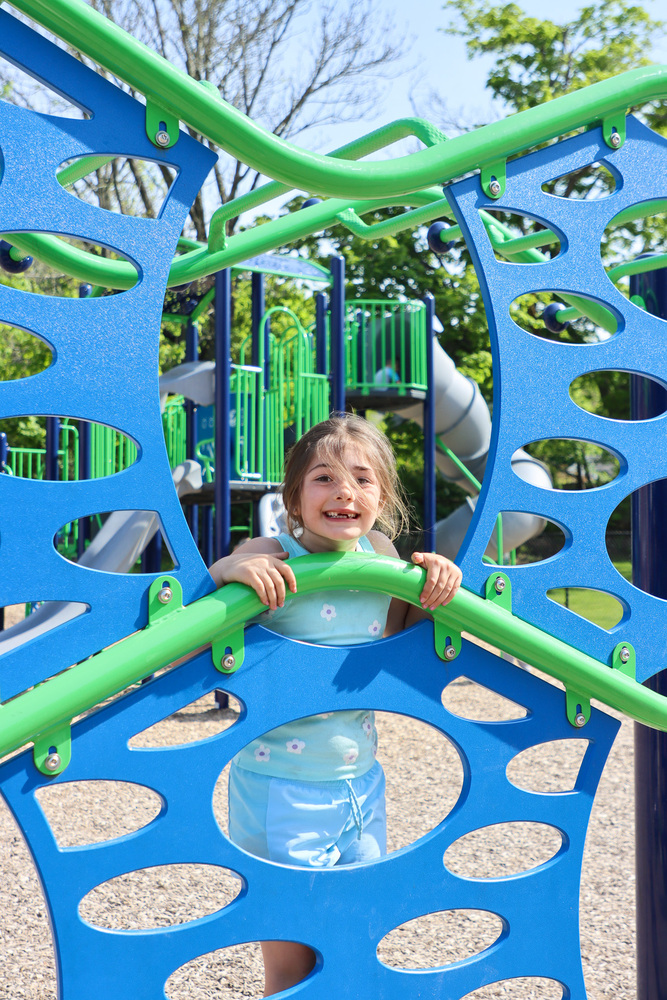 Student smiles while climbing on the new playground.