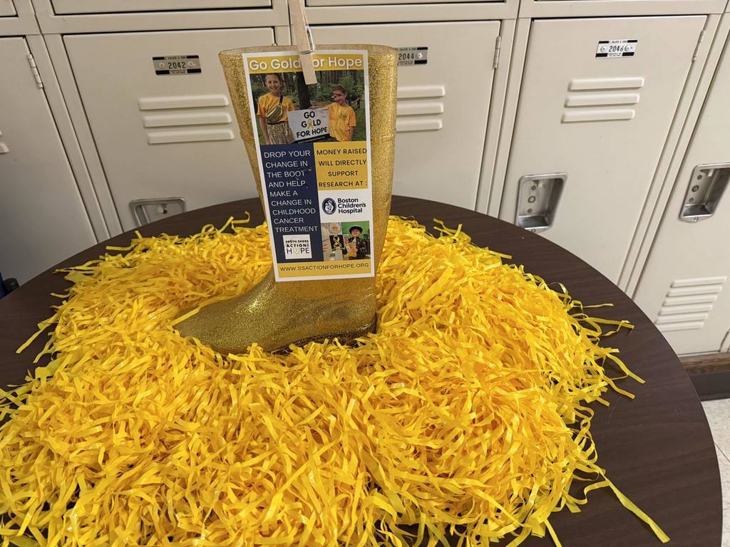 Gold boot with yellow confetti in front of lockers used to collect donations