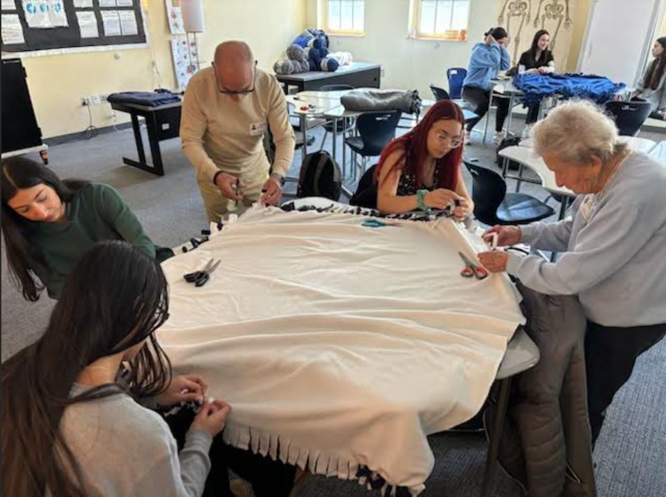 students and adults making blankets