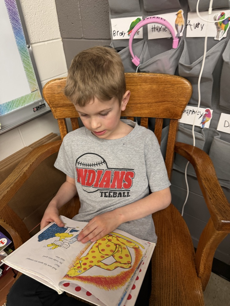 A kindergartener is reading a Dr Seuss book