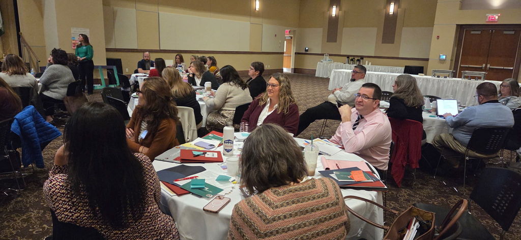 Melissa Jordan and Phillip anderson seated at a table of PCS educators at STRIVE conference.