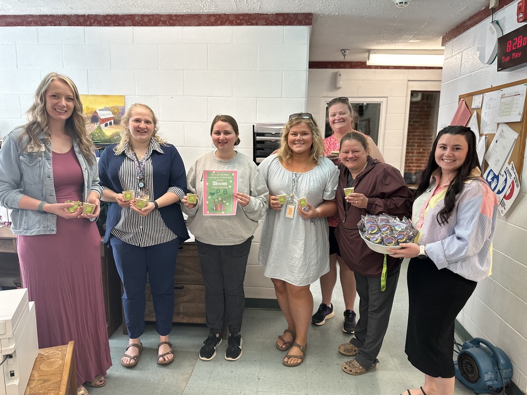 MES staff members stand together with PCB employees holding small appreciation gifts and a basket of treats, recognizing Teacher Appreciation Week support.