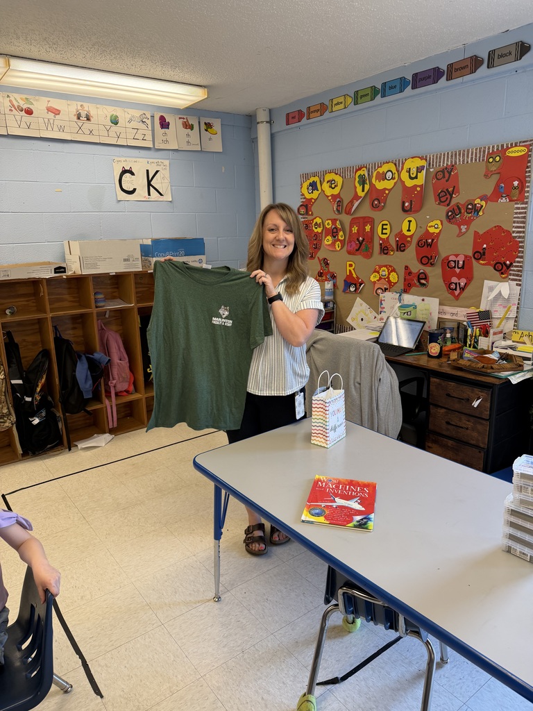  A staff member in a classroom holds up a green “Marlinton Faculty & Staff” T-shirt received as part of Teacher Appreciation Week.