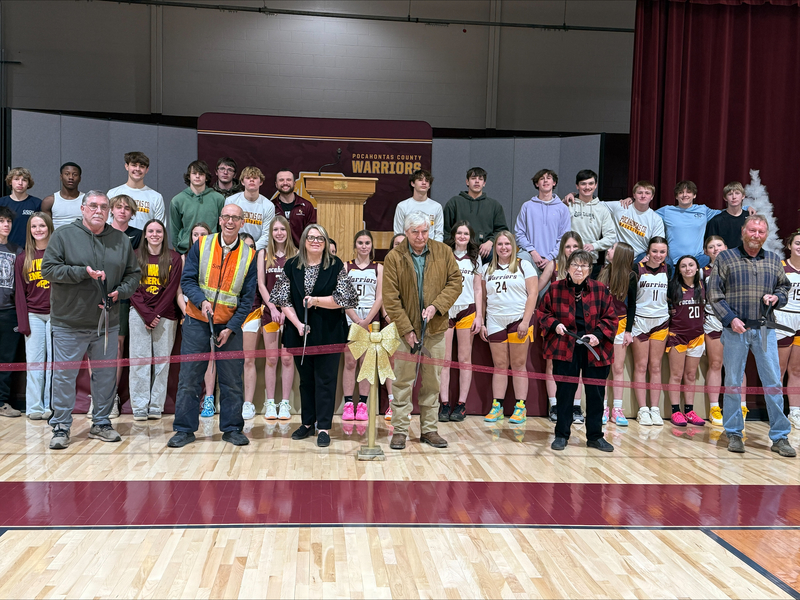 Members of the Pocahontas County BOE curring ribbon on gym floor with students in background