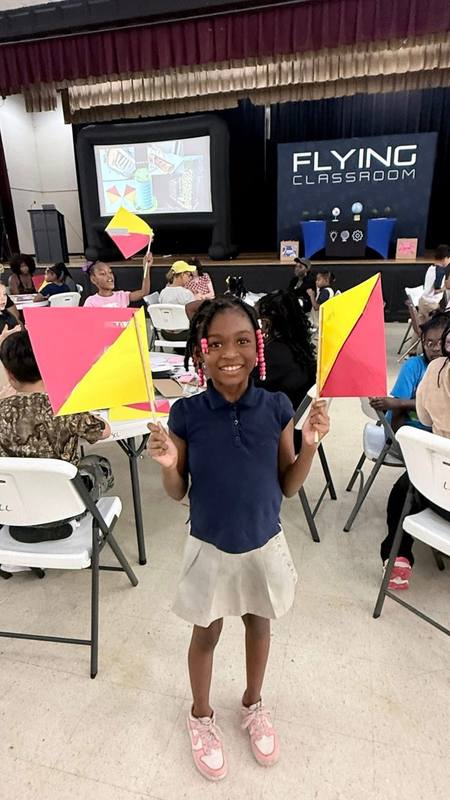 student smiling holding which she had created a event