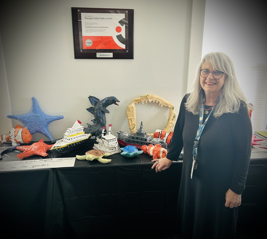 Art teacher proudly displaying her students’  artwork. 