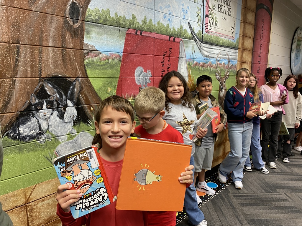 students holding their new library books up and smiling
