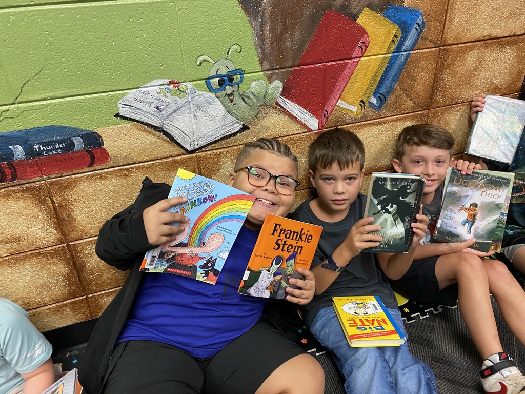 students holding their new library books up and smiling
